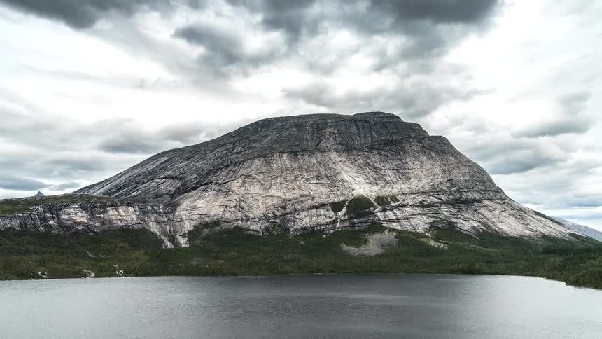 Landscape of a rocky mountain in front of the sea with clouds passing by in timelapse