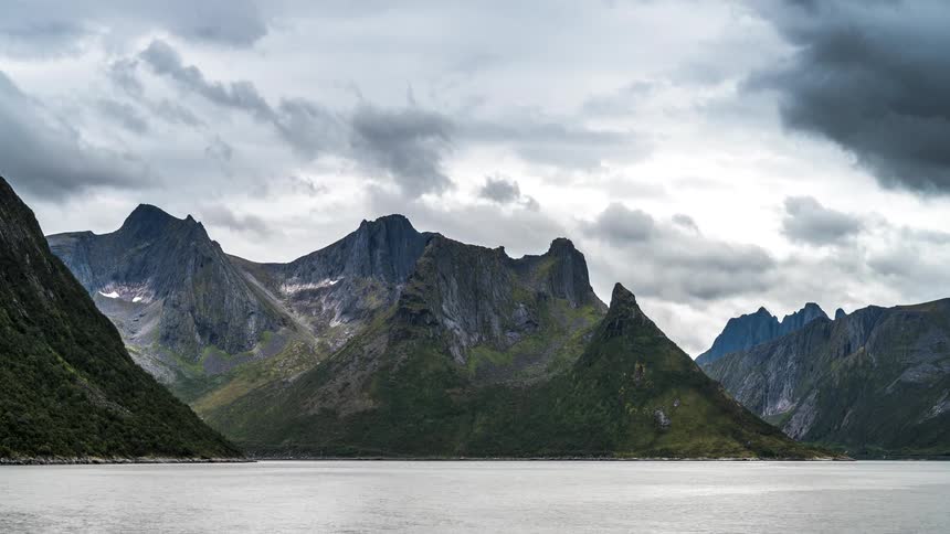 Landscape of mountain ranges facing the sea with clouds passing by in timelapse