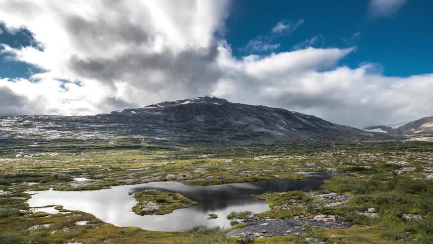 Aerial of a small lake in a field with mountains