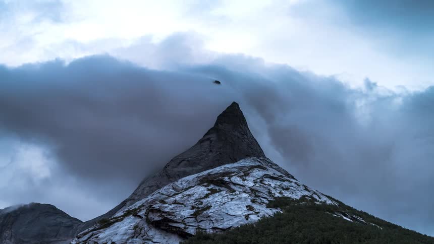 Mountain peak with a cliff with clouds passing over it in timelapse