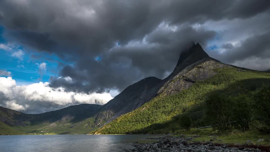 The clouds float over rocky mountains near the lake