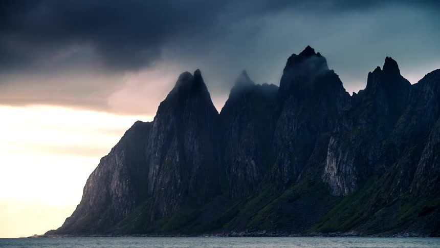 Panorama of a rocky mountain with cliffs and clouds passing over it in time lapse