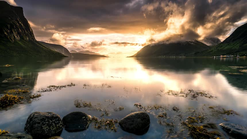A lake surrounded by mountains that reflect sunlight