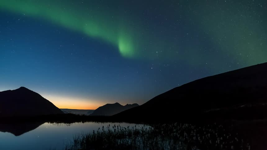 By the shore of a serene lake the northern lights gracefully dance across the night sky their vibrant hues reflecting on the tranquil water below