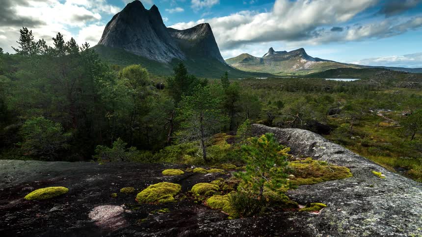Natural landscape of forests amidst hills and mountains with electric clouds passing by