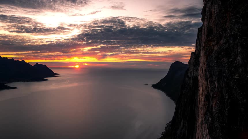 Timelapse landscape with the sun setting in the middle of the sea over the coast
