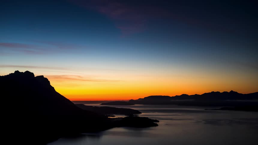 An orange sky in the morning in a region with a silhouette of a stone mountain