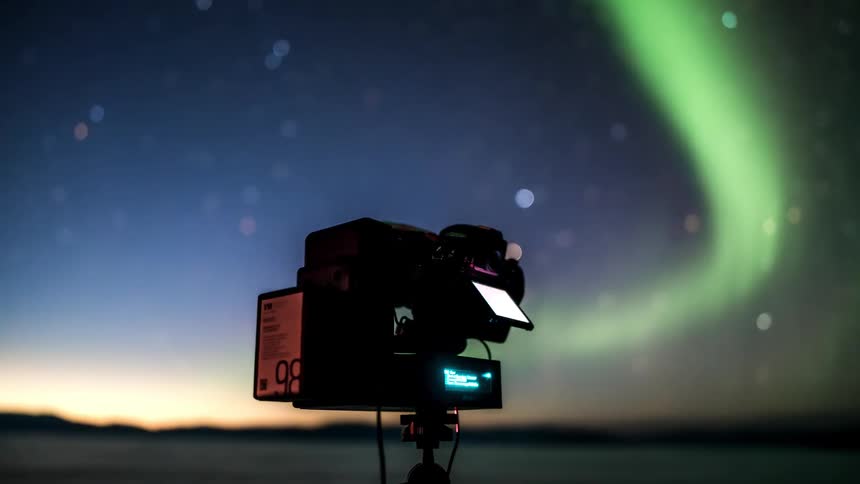 Professional camera capturing a landscape of a sky with aurora borealis