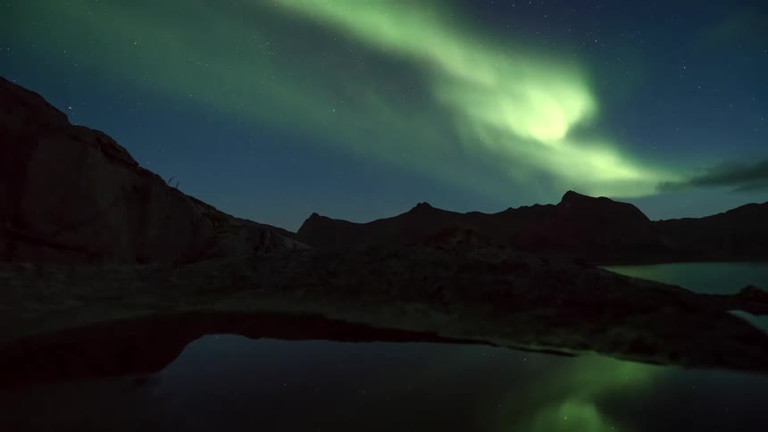 Natural landscape of mountains and a reflective lake with the night sky with aurora borealis