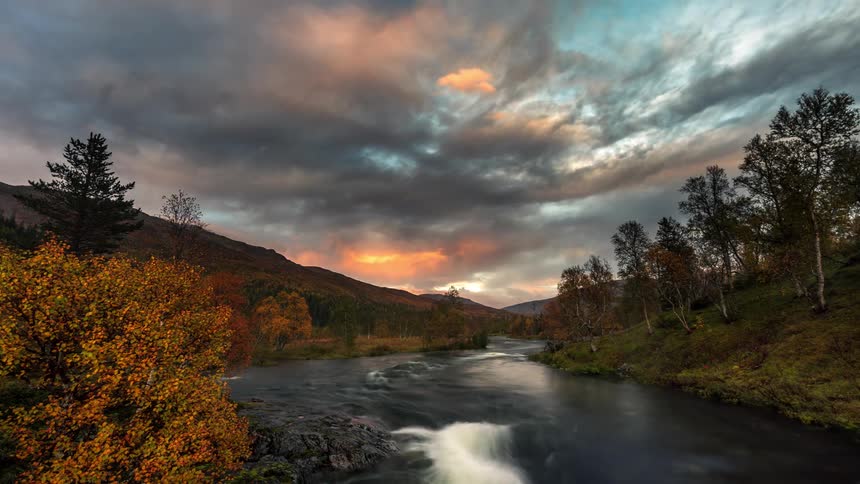 A time lapse clip of a flowing river beside the woods