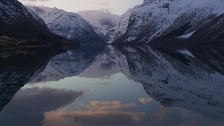 Against the backdrop of a dusky fjord a snowy mountain range stands tall