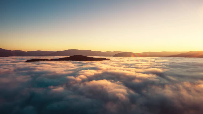Aerial panorama of clouds above the mountains and a morning sky with the sun