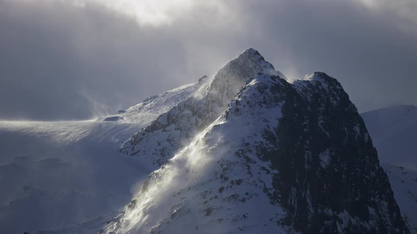 Landscape of a mountain with cliffs covered by snow and sun reflection on a cloudy day