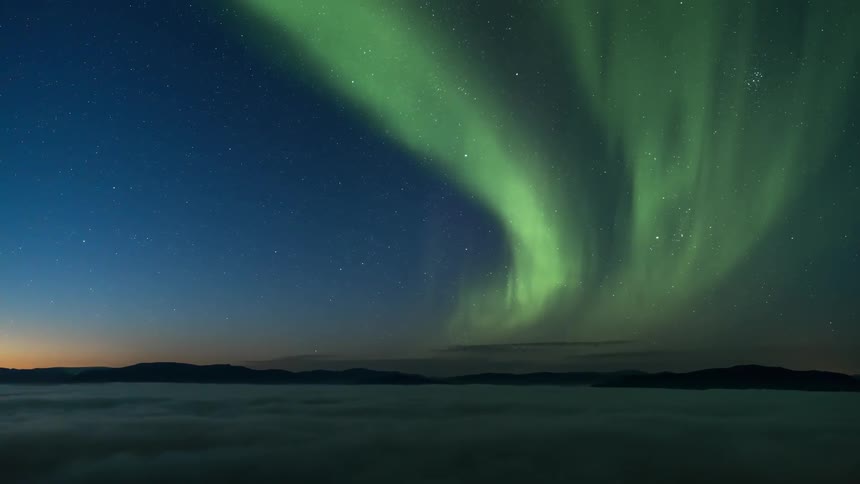 The northern lights playing across the night sky seen from a mountain top