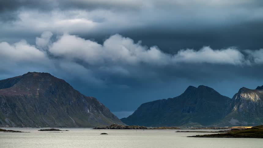 A region with two large mountains and many clouds passing in the sky to the left
