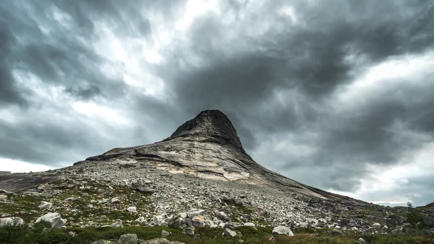 Mountain with a rocky peak and black clouds passing by in timelapse