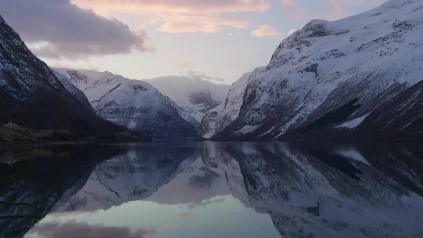A lake perfectly reflecting the snowy mountains and sky above it