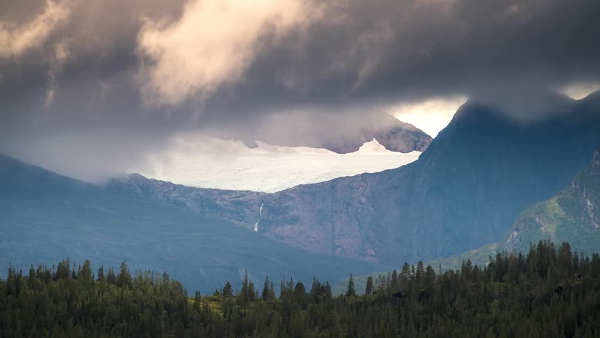 Time lapse of fog rolling over a forest and a mountain range