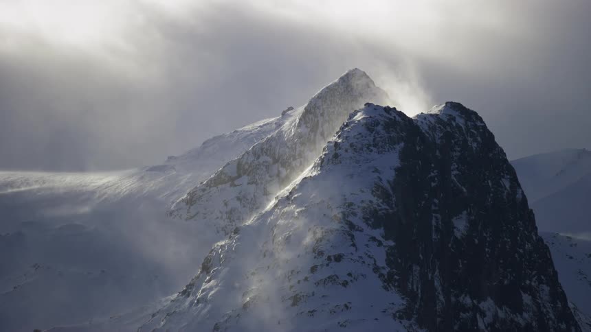 Mountains with cliffs covered in snow and solar reflection and a day with clouds