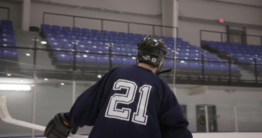 A hockey player skates on the ice in an empty arena