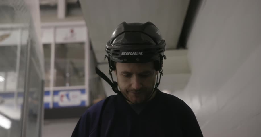 A man wearing a hockey helmet walks inside a building