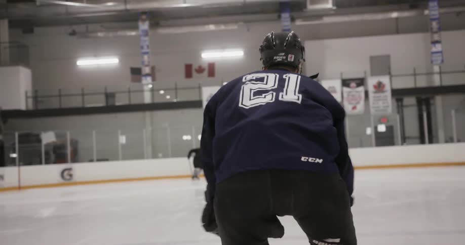 A hockey player is skating swiftly on the ice