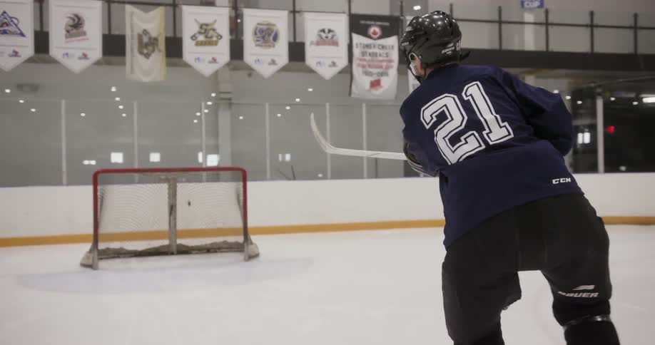 A hockey player hits a puck into a goal