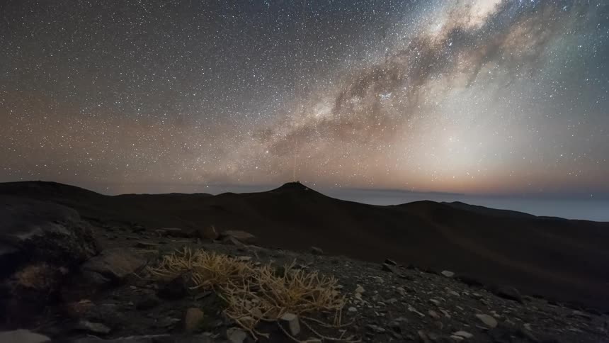 A rural region with a small mountain and the sky is full of stars