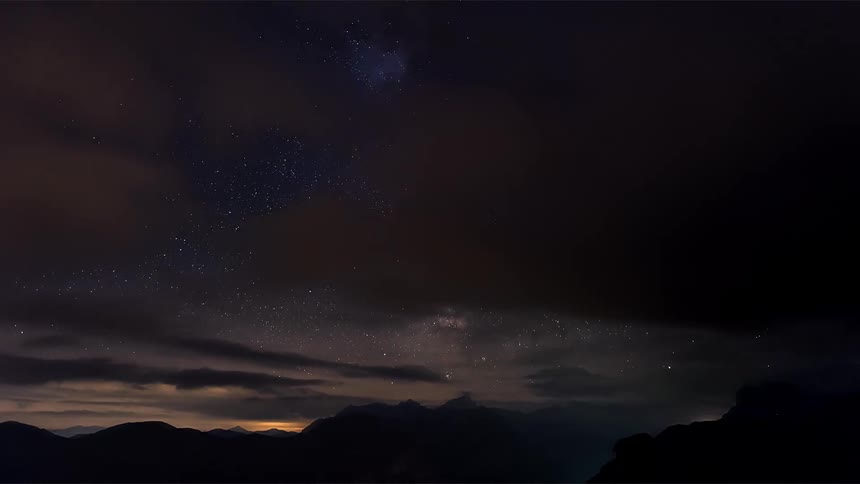 Starry sky landscape with cosmos and clouds passing by in timelapse