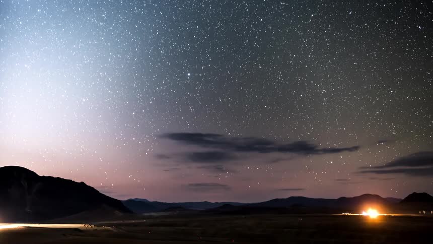 A galaxy seen at night gives way to a rising sun