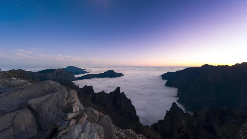 Clouds flow over the top of the mountain