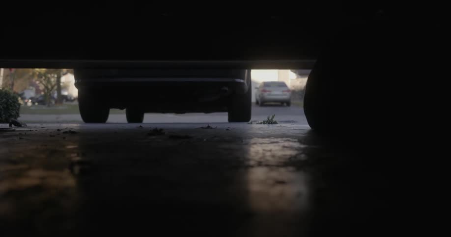 A garage door opens and a man walks towards a car