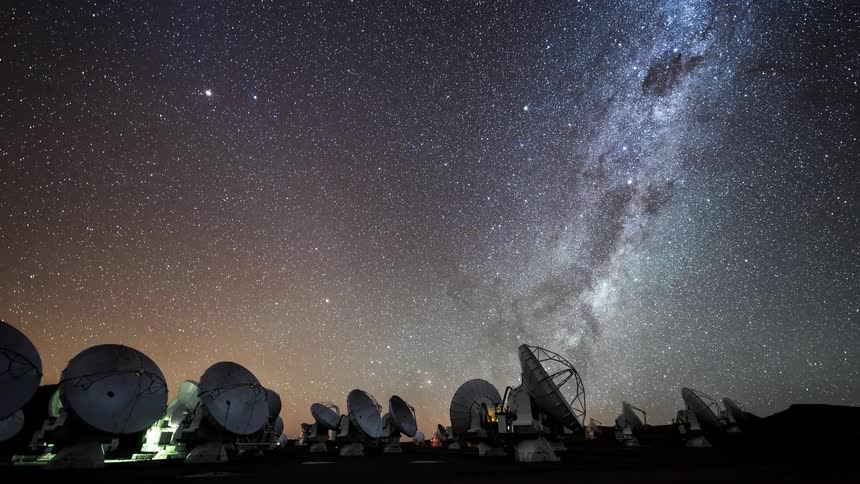 An observatory full of radio telescopes facing the sky that becomes dusk and stars all over