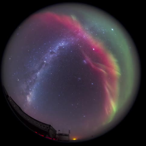 fisheye view of the milkyway galaxy partially covered by a aurora above a facility