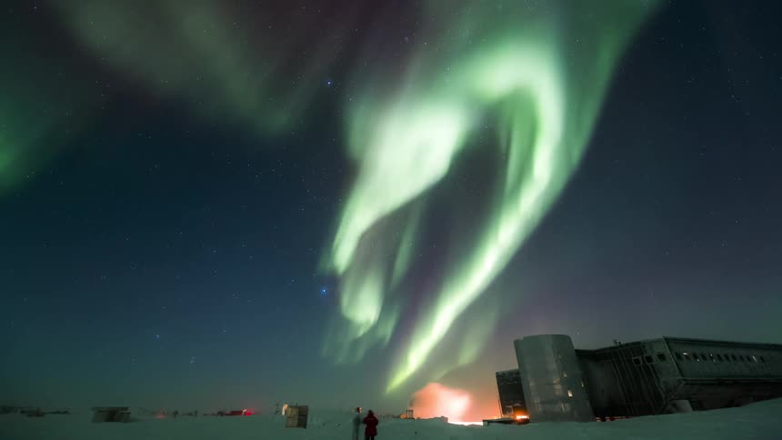 Aurora Australis with a lit research station and people