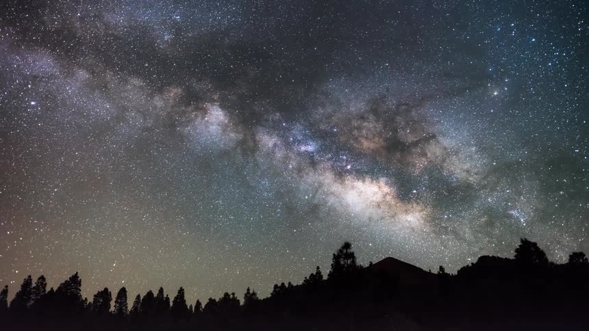 The milky way flows over the dark forest