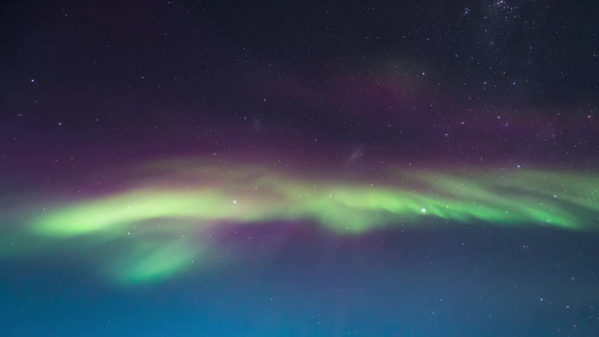 An aurora flickers in the sky during the dawn hours