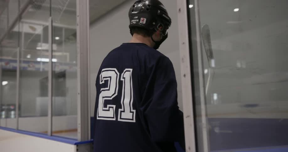 Man wearing his hockey uniform leaving the ice rink area and walking down the hall