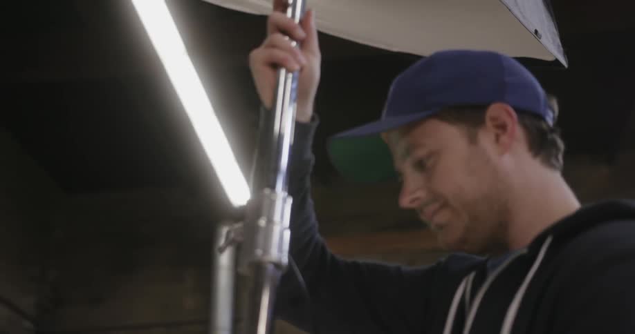 A man wearing a baseball cap adjusts a chrome stand