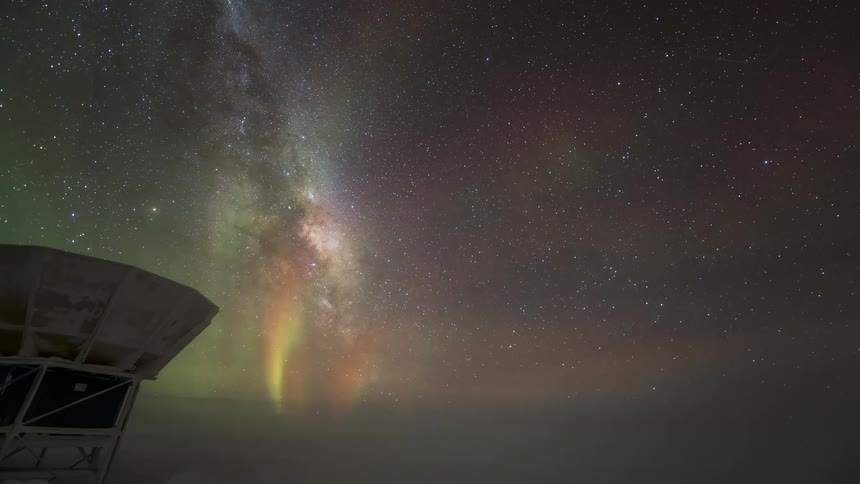 The Aurora Australis glows above a satellite dish under the stars of the milky way in the night sky
