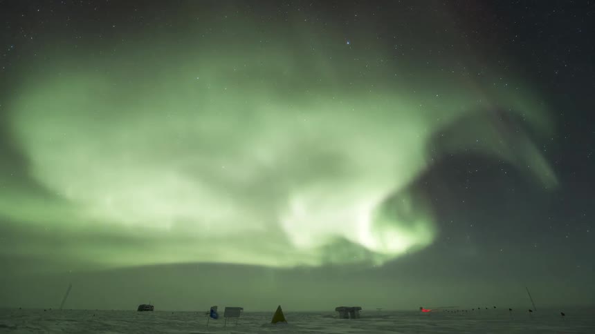 An aurora in the night sky over scattered ground structures