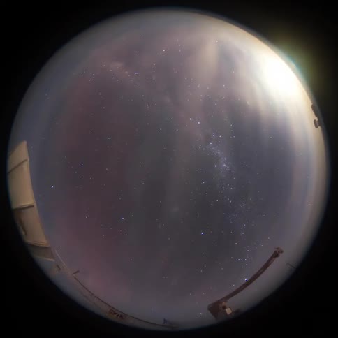 A view of the starry sky from a fish lens and there is a green beam of an aurora