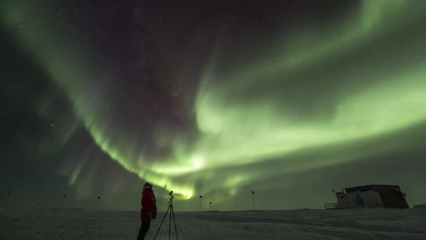 Person at the south pole looking at the night sky with Aurora Australis