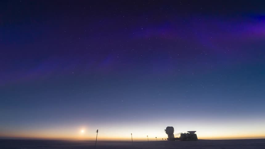 Landscape of an observatory at the south pole in an early evening sky with bluish and purple Aurora Australis
