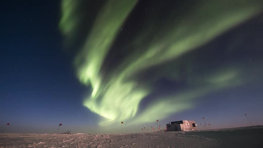 An aurora lights up the sky over a building