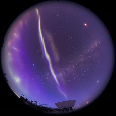 An aurora flashes in the sky near an observatory