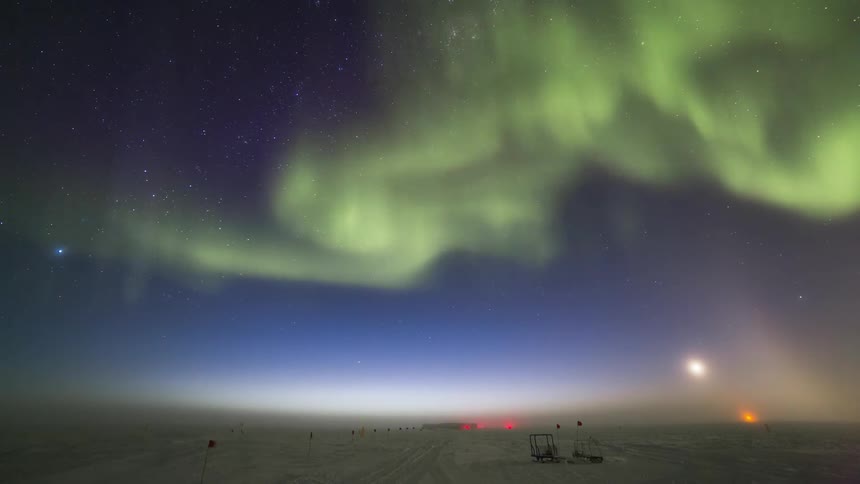 Landscape of the ground covered by snow and the night sky in timelapse with Aurora Australis