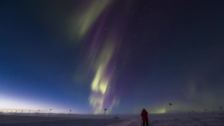 Two people go outside to take pictures of an aurora