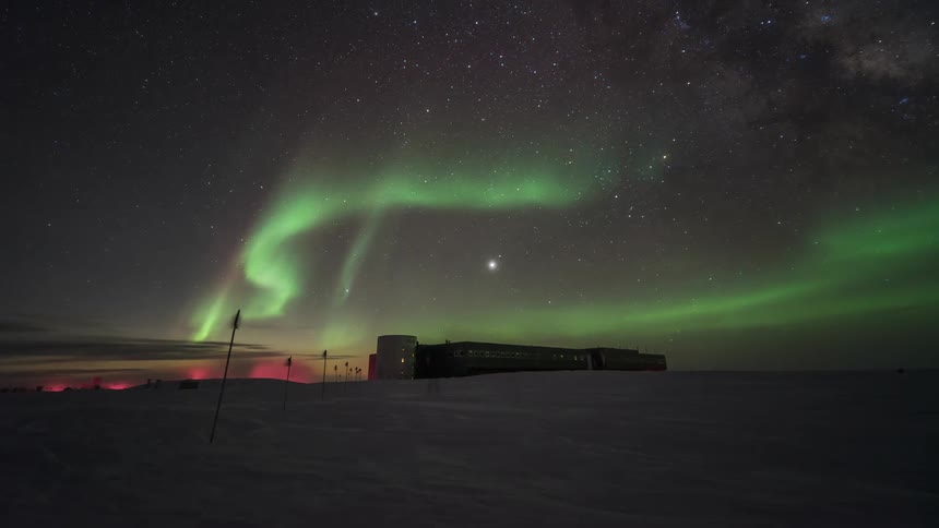People walk in the snow under the Aurora Australis