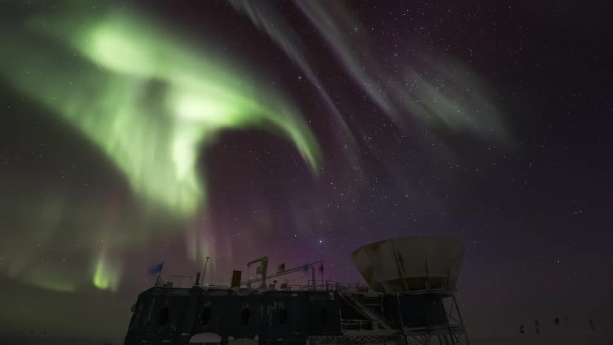 An observatory in antarctica where there is a green Aurora Australis in the sky